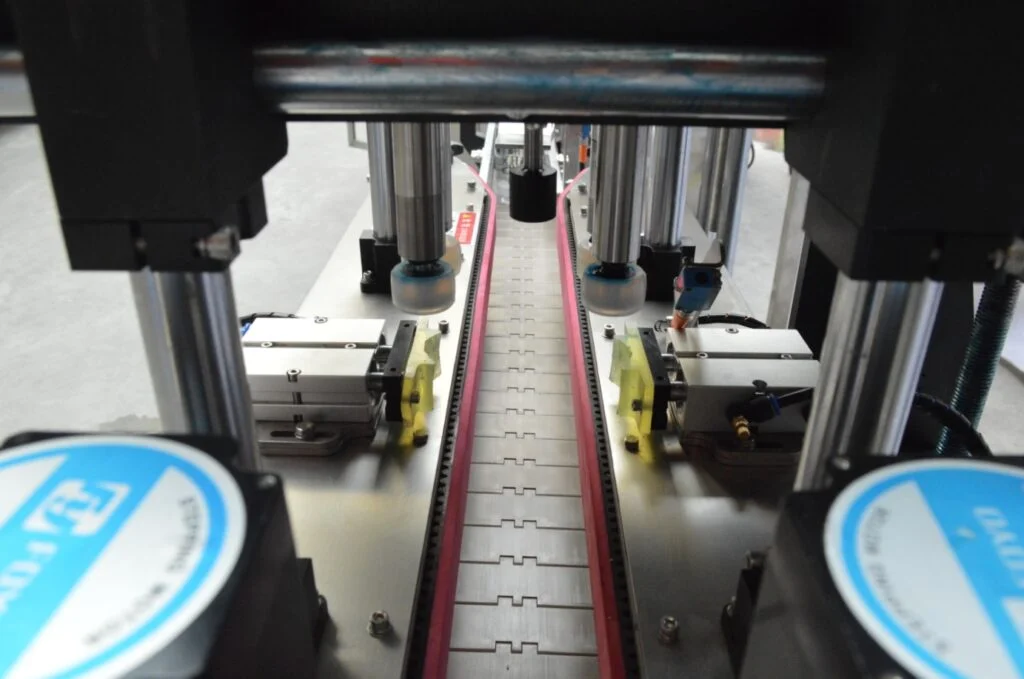 Close-up view of an automated conveyor system with mechanical parts and sensors, showcasing advanced packaging equipment supported by expert installation and training for efficient industrial manufacturing.