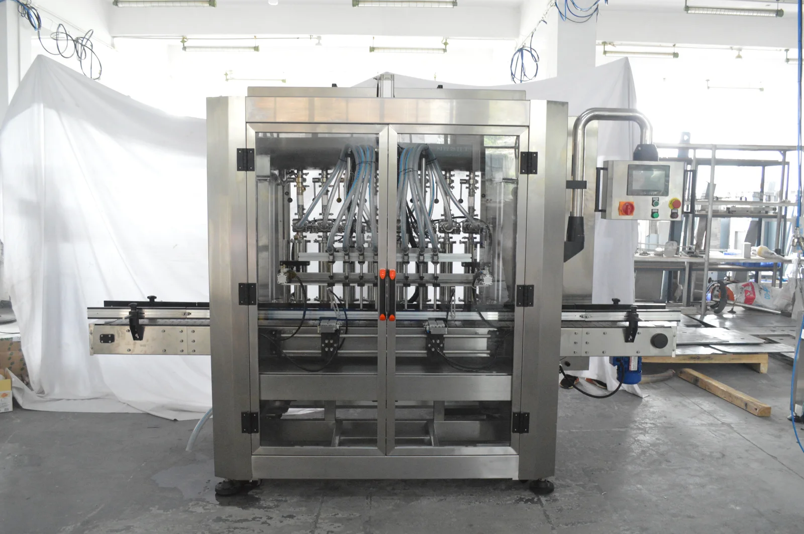 Liquid Filling Machine operating in a high-speed production line to dispense precise fluid volumes into clear glass bottles.