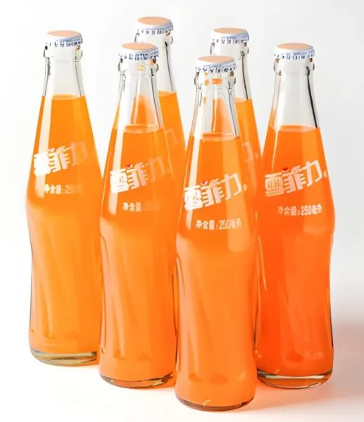 Glass bottles filled with orange beverage on production line