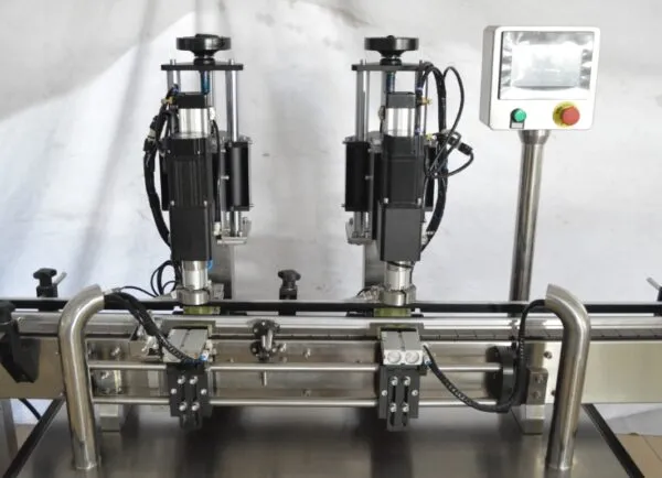 Dual-head capping machine operating on a conveyor line