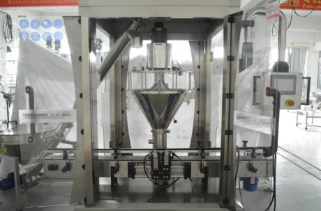A stainless steel Powder Filling Machine stands in a factory setting, featuring a transparent front panel, various control buttons, and a conveyor belt beneath the filling nozzle.