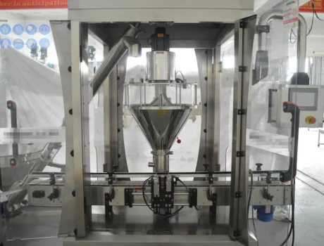 A stainless steel Powder Filling Machine stands in a factory setting, featuring a transparent front panel, various control buttons, and a conveyor belt beneath the filling nozzle.