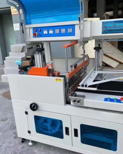 Shrink wrap packaging machine with conveyor belt and control panel, used for product protection.