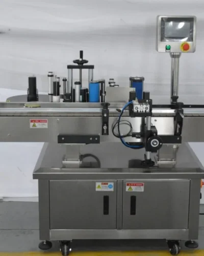 A stainless steel Round Bottle Labeling Machine with a conveyor belt, control panel, and rollers, designed for applying labels to bottles or containers in an industrial setting.