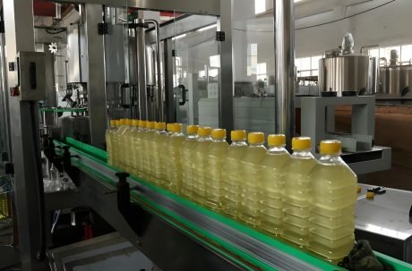 Automatic bottle filling machine processing liquid bottles on conveyor