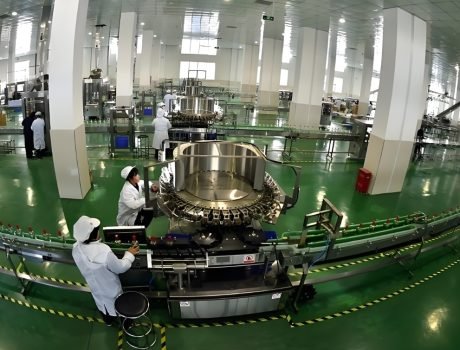 Rotary bottle filling machine operating in beverage factory