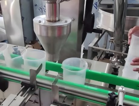 Powder filling machine dispensing product into plastic containers