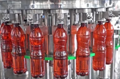 Plastic bottles filled with red beverage on production line