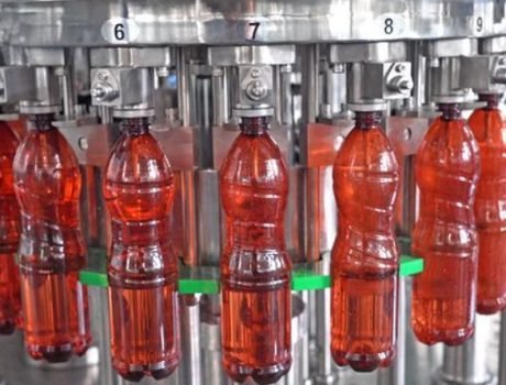 Plastic bottles filled with red beverage on production line