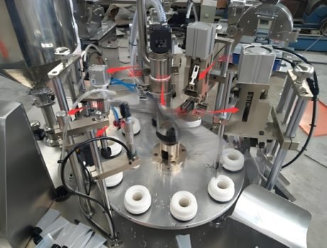 Filling machine dispensing product into tubes with precise automation.