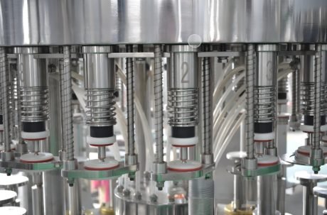 Bottles moving on a conveyor for filling and capping in an automated system.