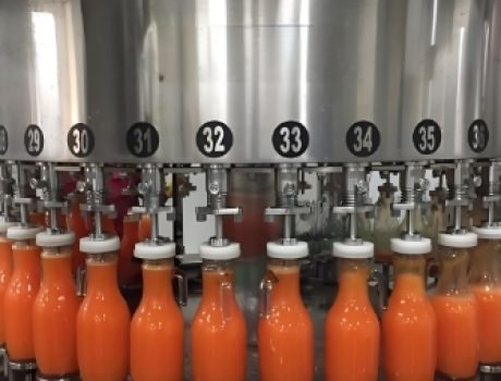 Automated beverage filling and capping machine sealing bottles.