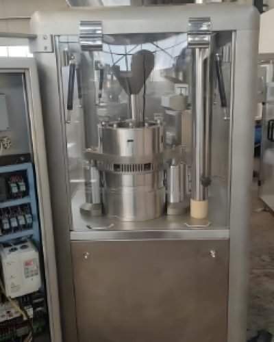 Capsule production machine sorting and filling orange capsules.