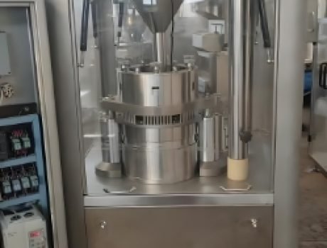 Capsule production machine sorting and filling orange capsules.