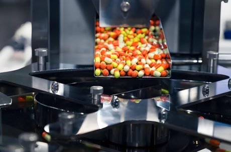 Capsules moving through a high-speed sorting and packaging system.