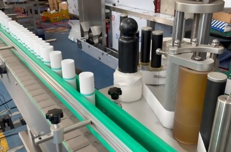 Labeling machine applying labels to cylindrical containers in a high-speed production line.