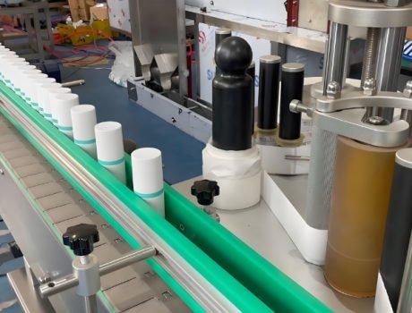 Labeling machine applying labels to cylindrical containers in a high-speed production line.