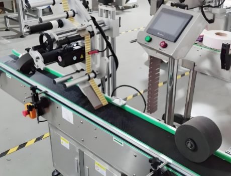 Conveyor system feeding bottles into an automated labeling machine for quick processing.