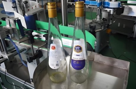 Bottles being labeled by a Labeling Machine on a production line, "Mango Juice" text visible.