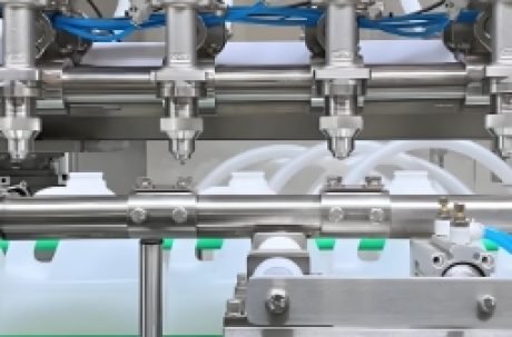 Automatic liquid filling machine nozzles filling bottles on a production line.