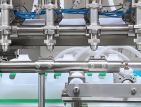 Automatic liquid filling machine nozzles filling bottles on a production line.
