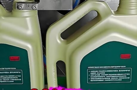 Close-up of an automatic liquid filling machine dispensing liquid into containers.